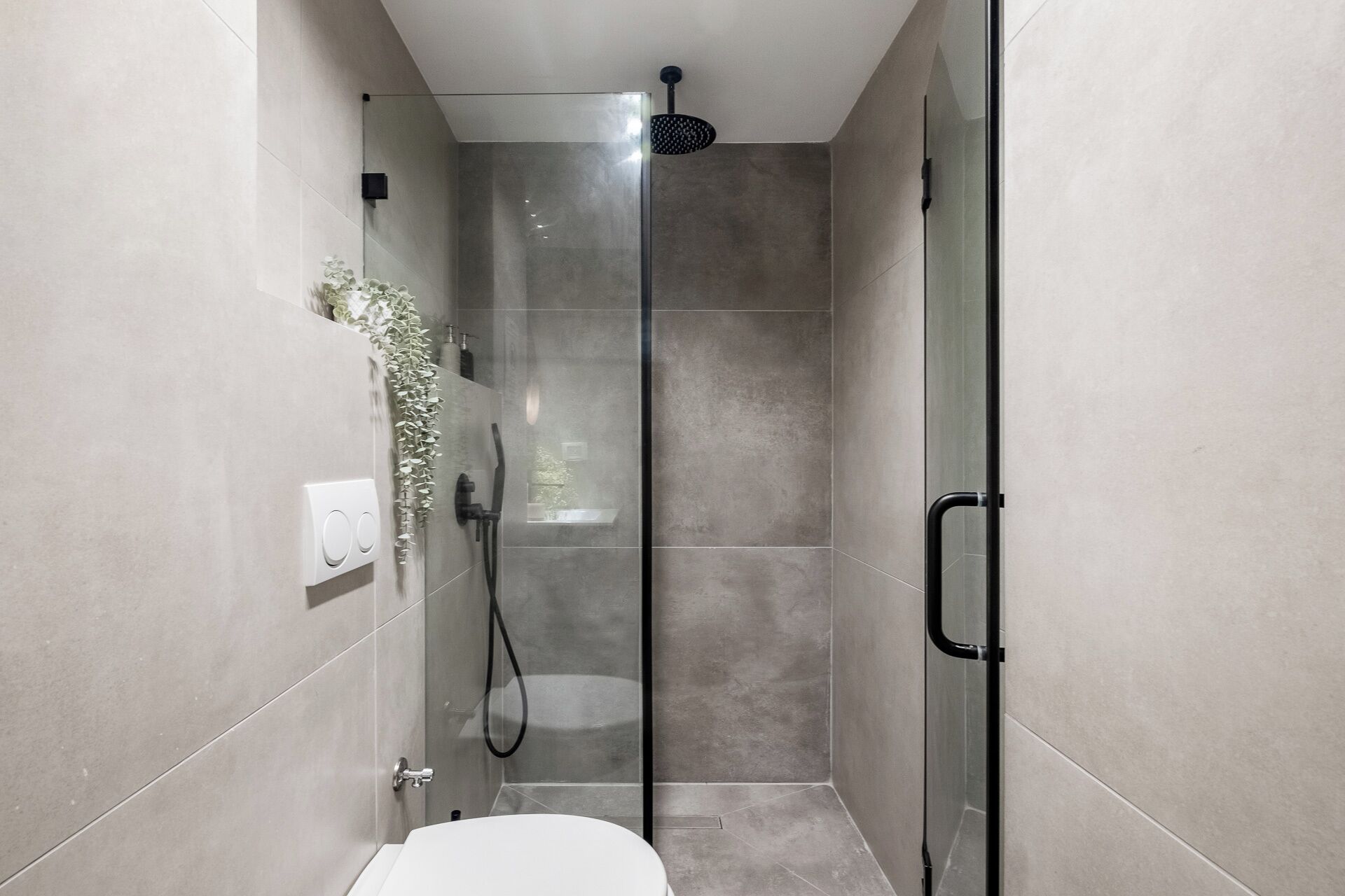Un baño moderno con cabina de ducha de vidrio, inodoro y grifo empotrado en la pared.