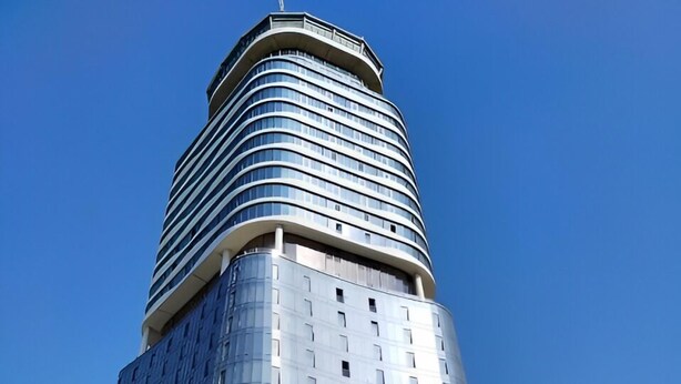 Ein modernes Hochhaus mit gewölbter Spitze und Glasfassade.