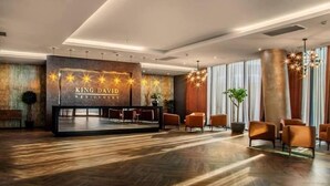 Ein modernes Hotel-Foyer mit Holzboden, einer Rezeption und mehreren orangefarbenen Sesseln.