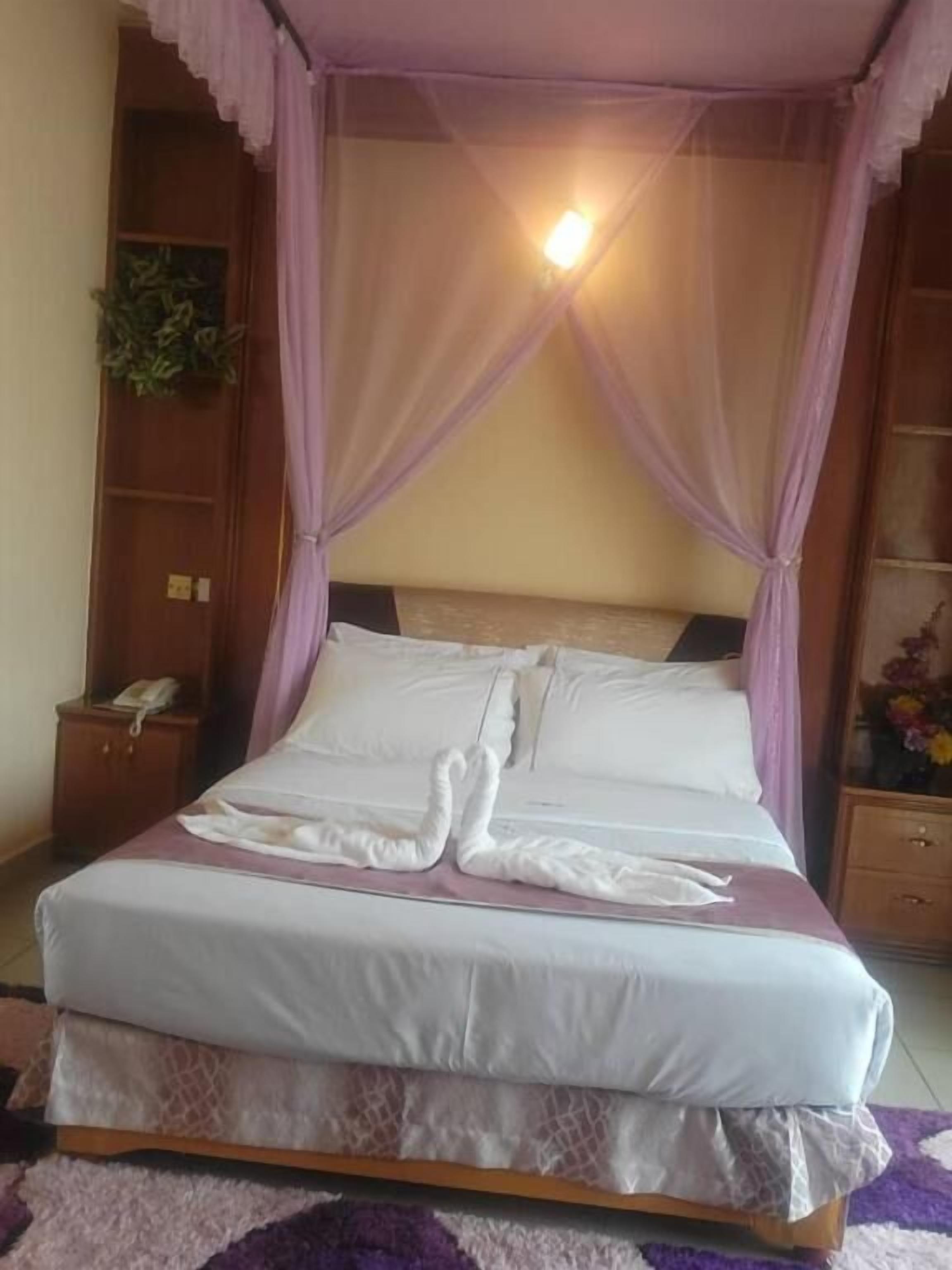 A neatly made bed with white linens and a decorative swan pillow arrangement.