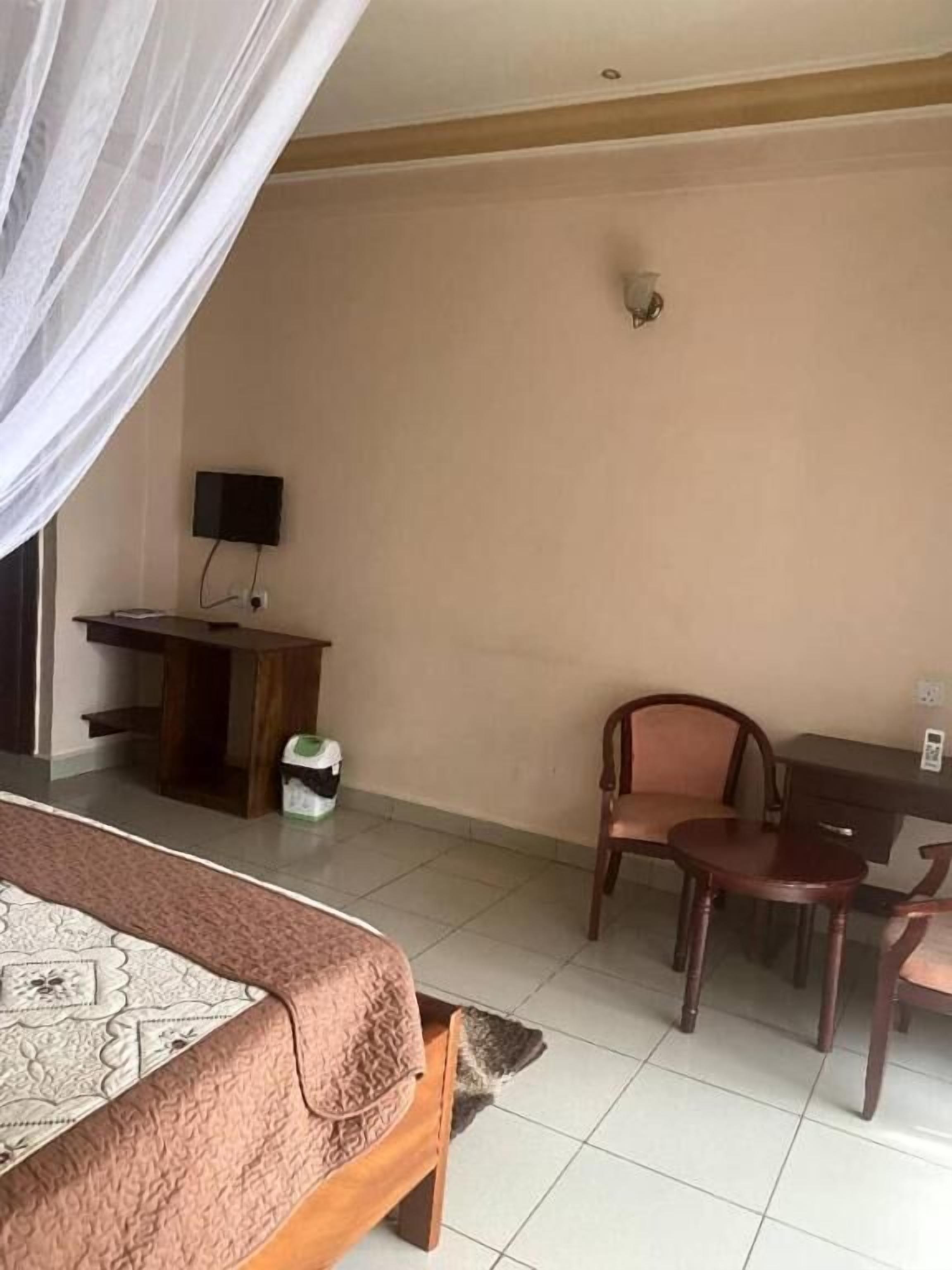 Una habitación de hotel con cama, escritorio, silla y televisor.