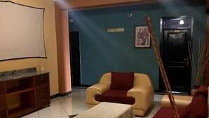 A living room with beige sofas, a small table, and a TV. - Tick Hotel (Kampala)