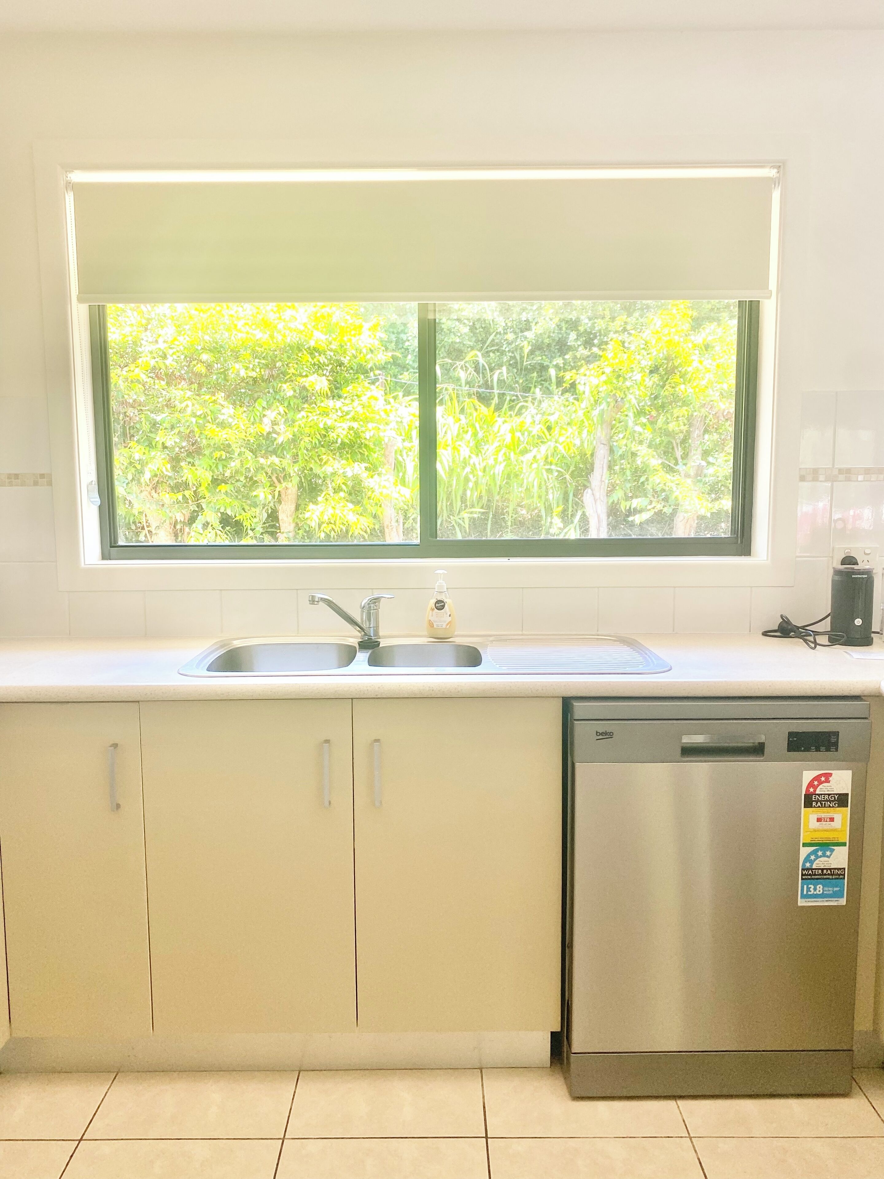 A kitchen with a window, sink, cabinets, and a dishwasher.