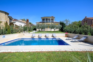 A swimming pool with lounge chairs, a stone building with a balcony, and a well-maintained garden. - Cosy Apartment With Fenced Garden (Porec)