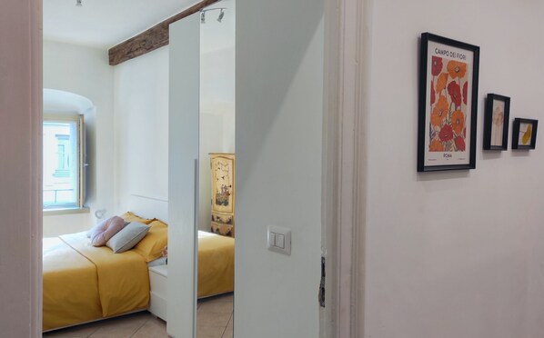 A bedroom with a bed, a wardrobe, and a window. There are framed pictures on the wall. - Conte Verde 8 by Wonderful Italy (Turin)
