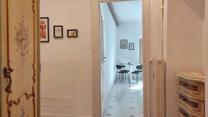 A hallway with a door leading to a dining area. There are framed pictures on the wall, a radiator, and a decorative wall panel. - Conte Verde 8 by Wonderful Italy (Turin)