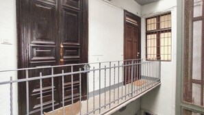A building with two dark wooden doors, a metal railing, and a barred window. - Conte Verde Studio 11 by Wonderful Italy (Turin)