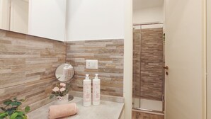 A bathroom with a stone backsplash, a mirror, a towel, and two bottles of organic hair and body wash. - Conte Verde Studio 11 by Wonderful Italy (Turin)