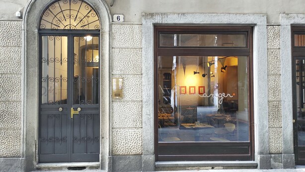 A building facade with a large arched window and a door, featuring a textured stone wall and a number '6' sign. - Conte Verde Studio 11 by Wonderful Italy (Turin)