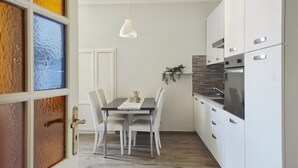 A modern kitchen with white cabinets, a stainless steel refrigerator, and a dining table with four chairs. - Conte Verde Studio 11 by Wonderful Italy (Turin)
