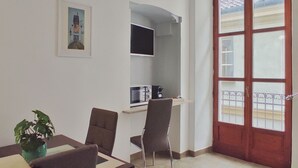 A dining area with a table, chairs, a potted plant, a microwave, and a television on a stand. - Conte Verde 10 con Balcone by Wonderful Italy (Turin)