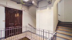 A staircase with a metal railing, a wooden door, and a wall with a light switch. - Conte Verde 10 con Balcone by Wonderful Italy (Turin)