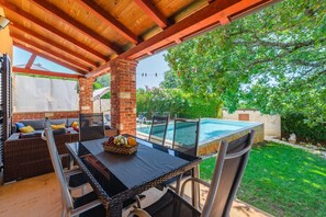 An outdoor patio with a pool, wicker furniture, and a stone wall. - Lovely Villa Near the Beach (Visnjan)