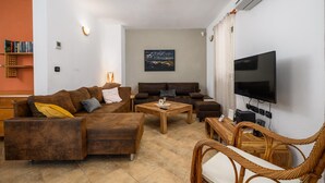 A living room with a sectional sofa, a coffee table, a TV, and a bookshelf.