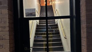 Una escalera que lleva a un piso superior, con un tapete que dice 'WELCOME' en la parte inferior.