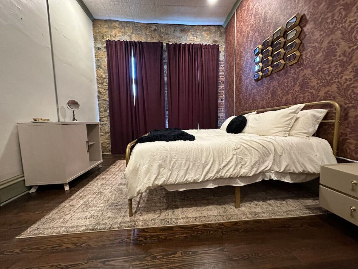 A bedroom with a bed, a dresser, a mirror, and a decorative wall piece.