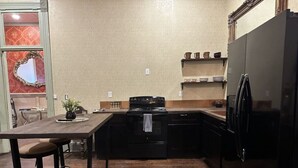 Una cocina compacta con piso de madera oscura, una estufa negra y un refrigerador.