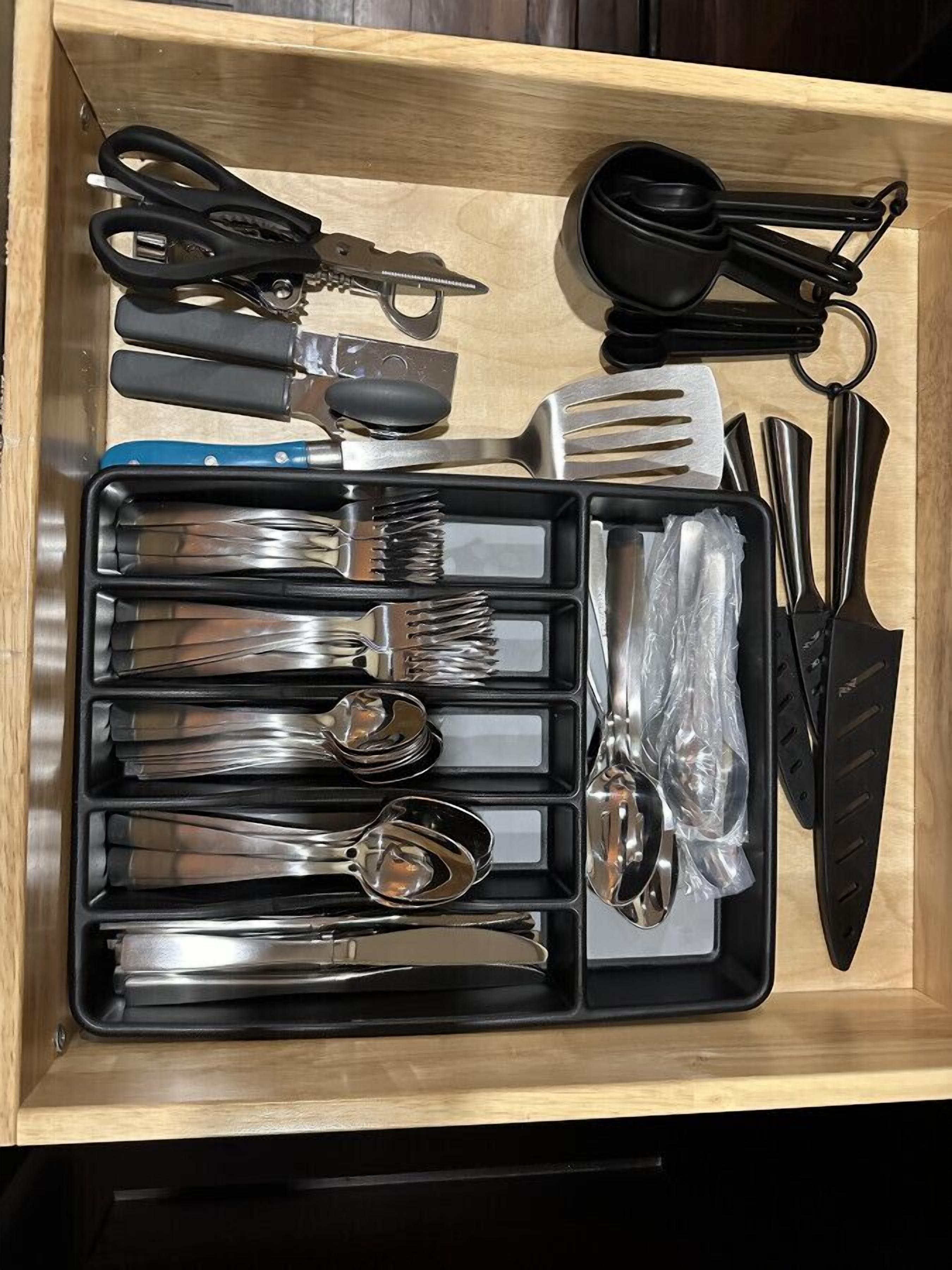 Eine Schublade mit verschiedenen Küchenutensilien, darunter Gabeln, Löffel, ein Messer und eine Schere.