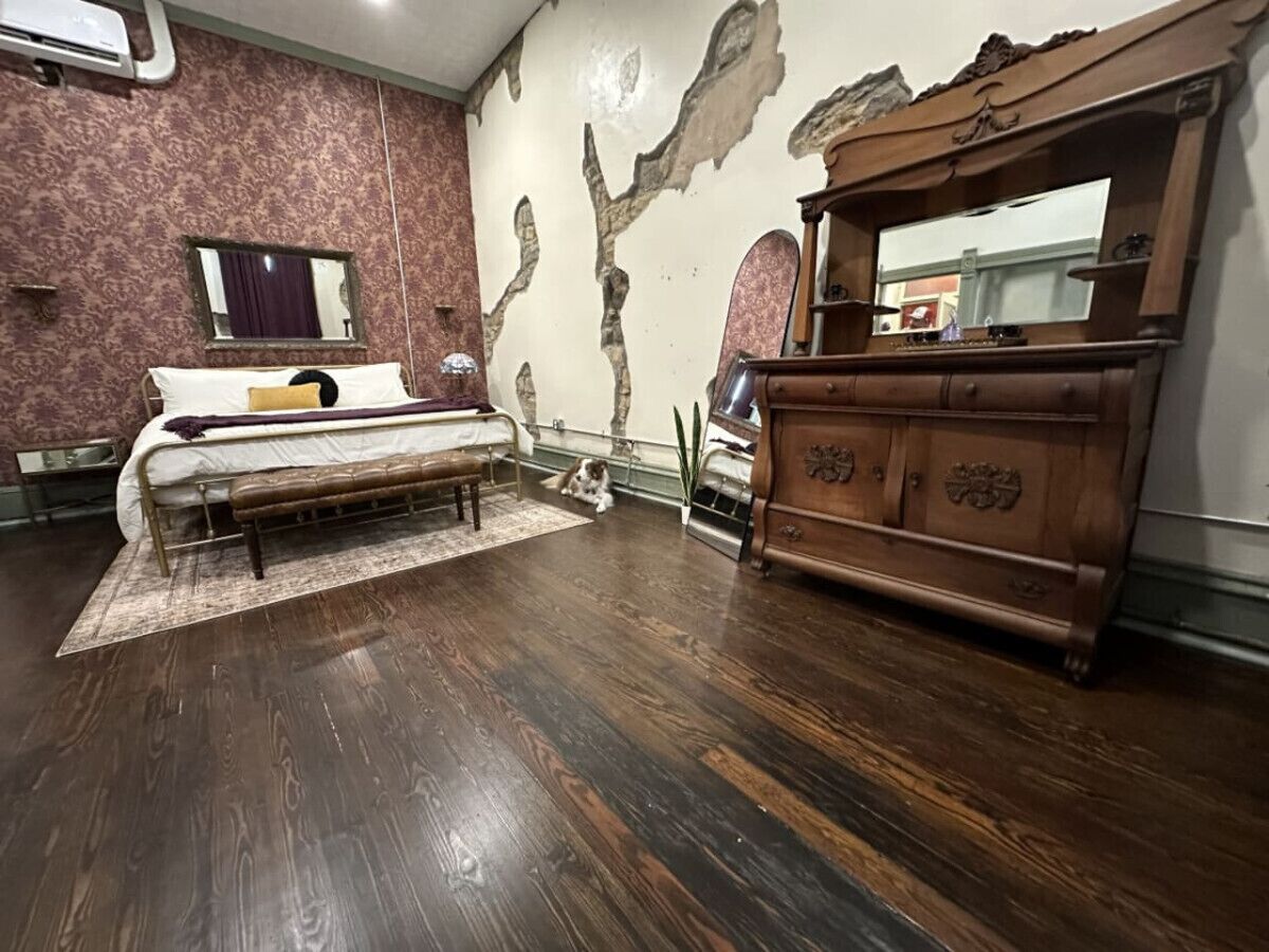 Une chambre à coucher avec un lit, une commode en bois et un miroir.