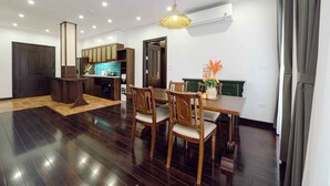 A modern kitchen with wooden cabinets, a dining area with a wooden table and chairs, and a pendant light.