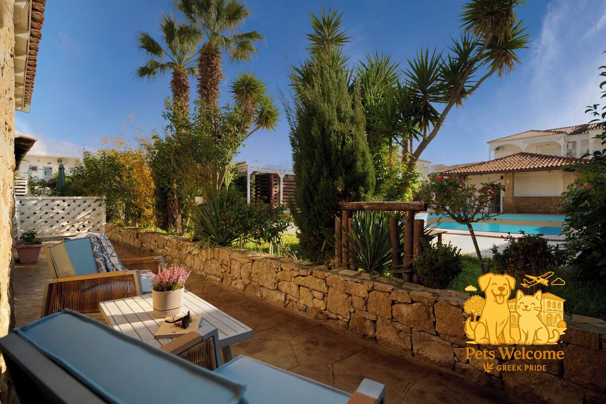 A patio with outdoor furniture, a stone wall, and a pool in the background.