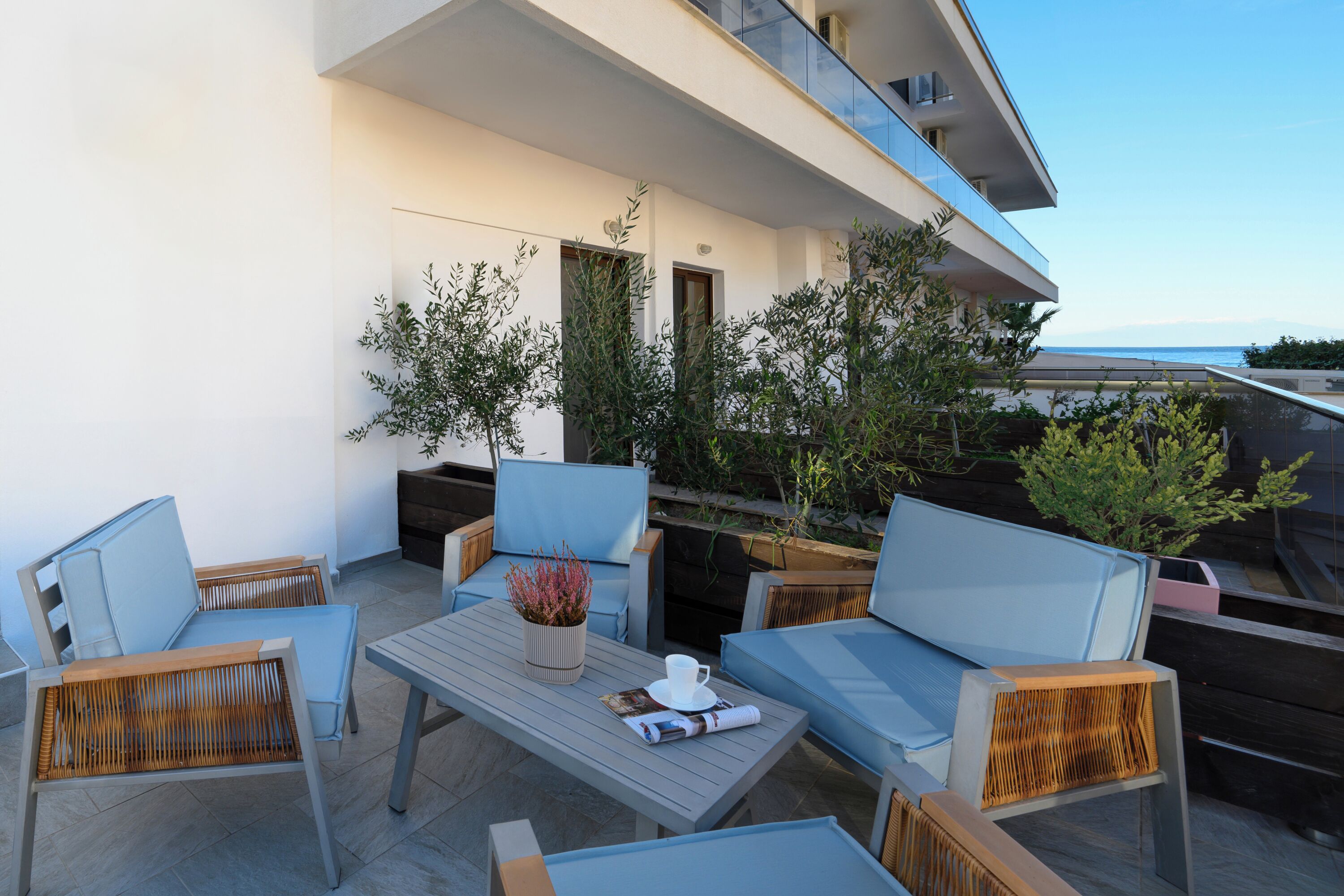A modern outdoor seating area with a table, chairs, and potted plants.