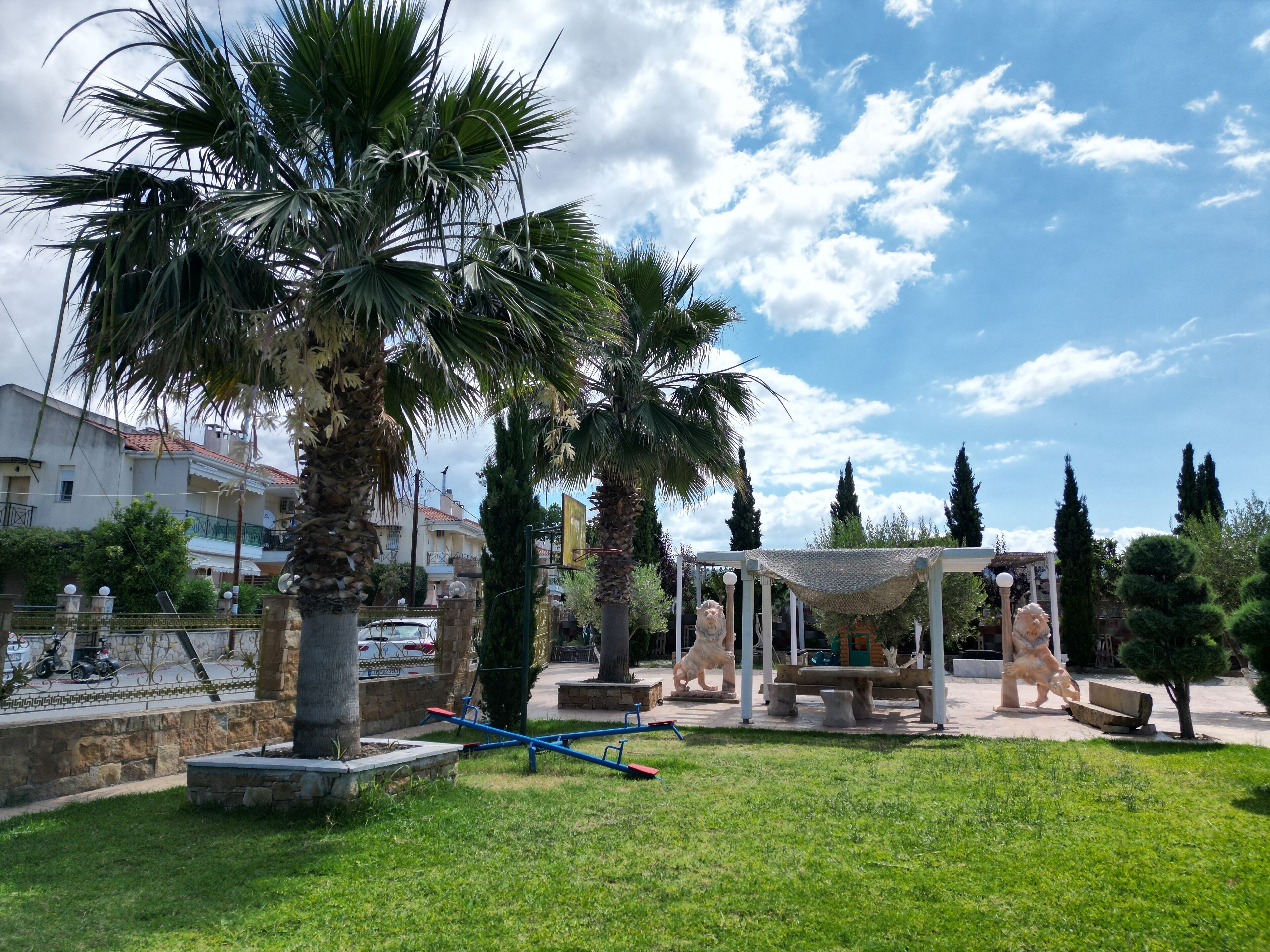 A park with exercise equipment, a gazebo, and palm trees.