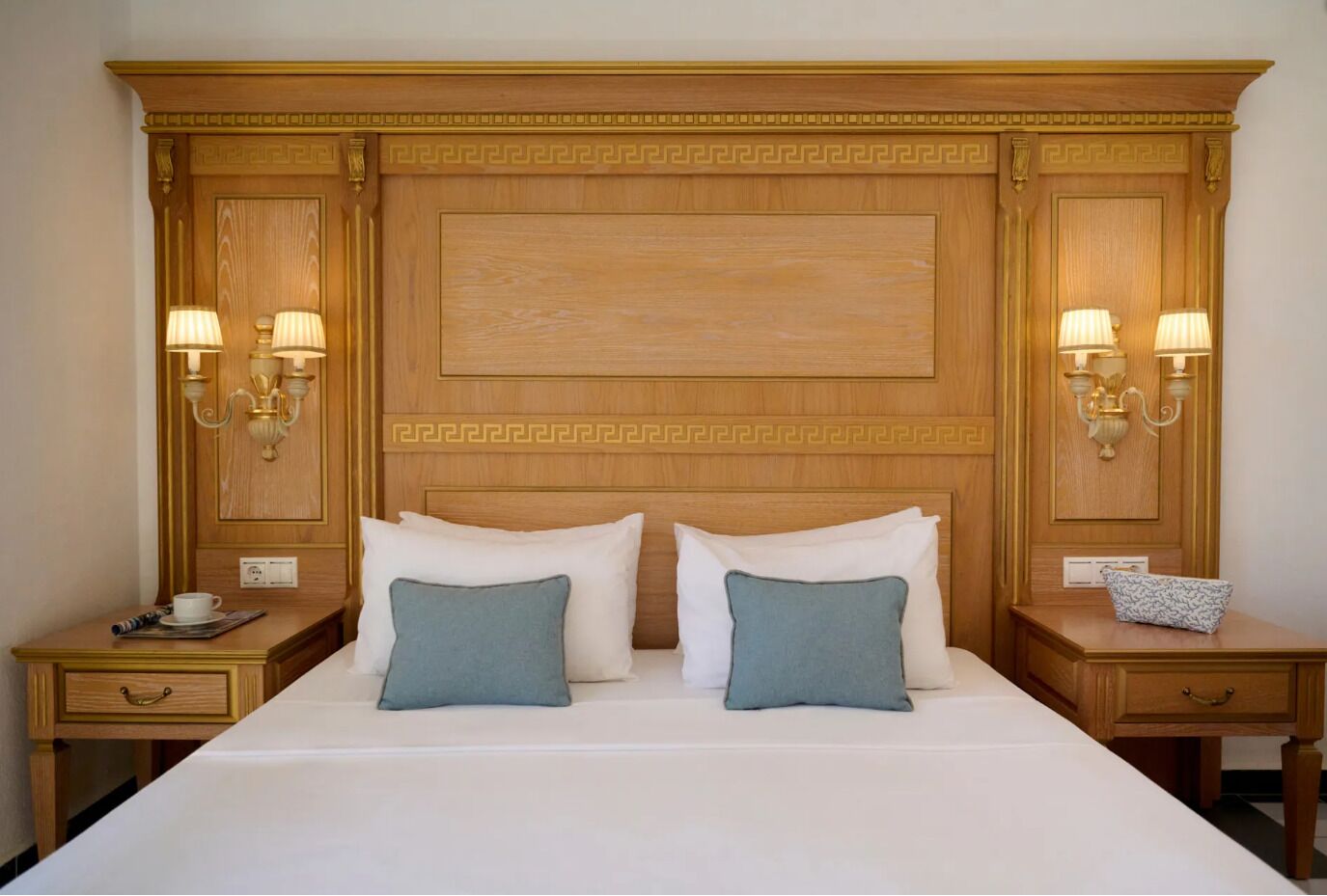 A hotel room with a large bed, two bedside tables with lamps, and a decorative headboard.