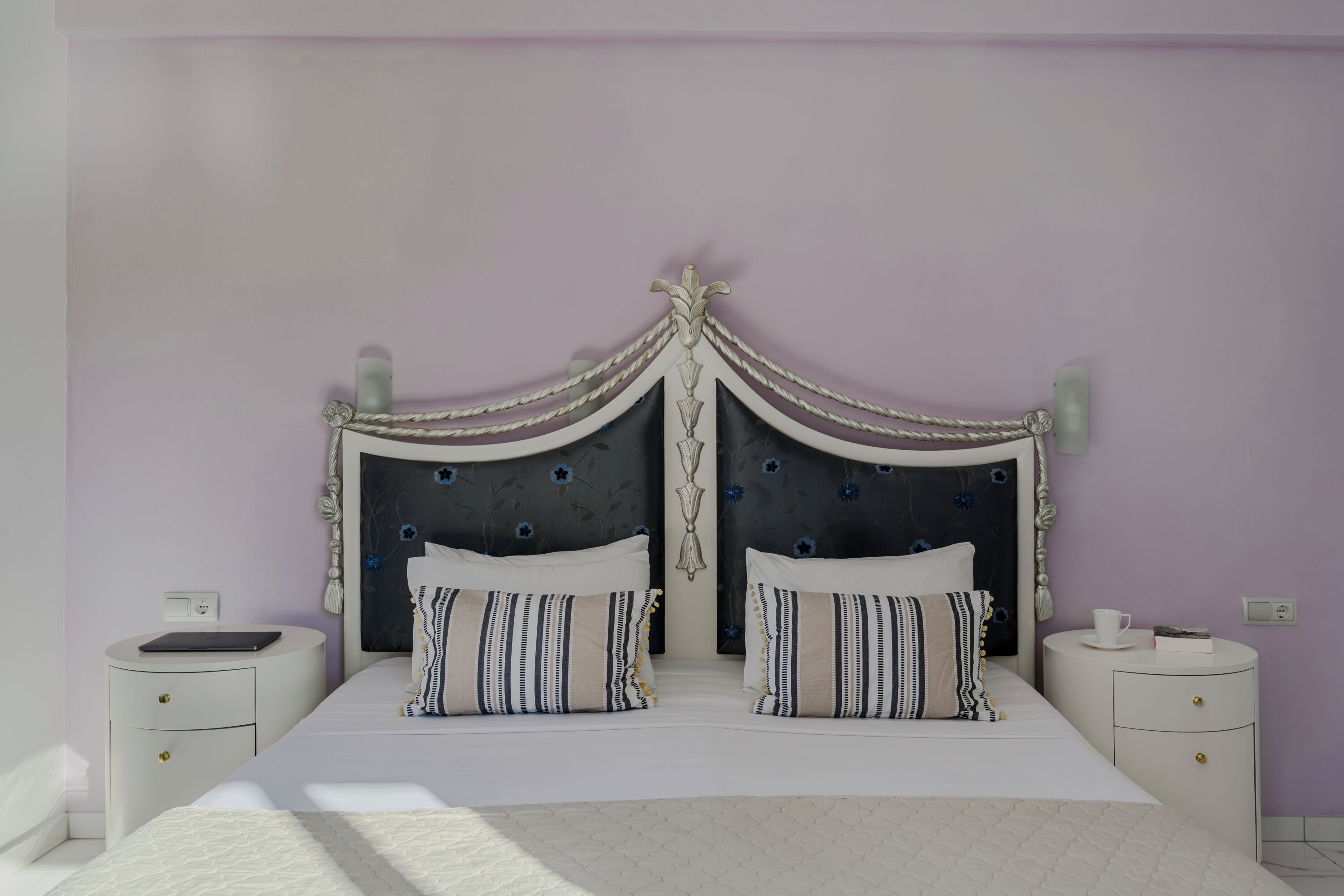 A bedroom with a large bed, two bedside tables, and a decorative headboard.