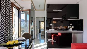 Una cocina moderna con cubierta de encimera negra, una silla roja y una zona de comedor con mesa y sillas de vidrio.