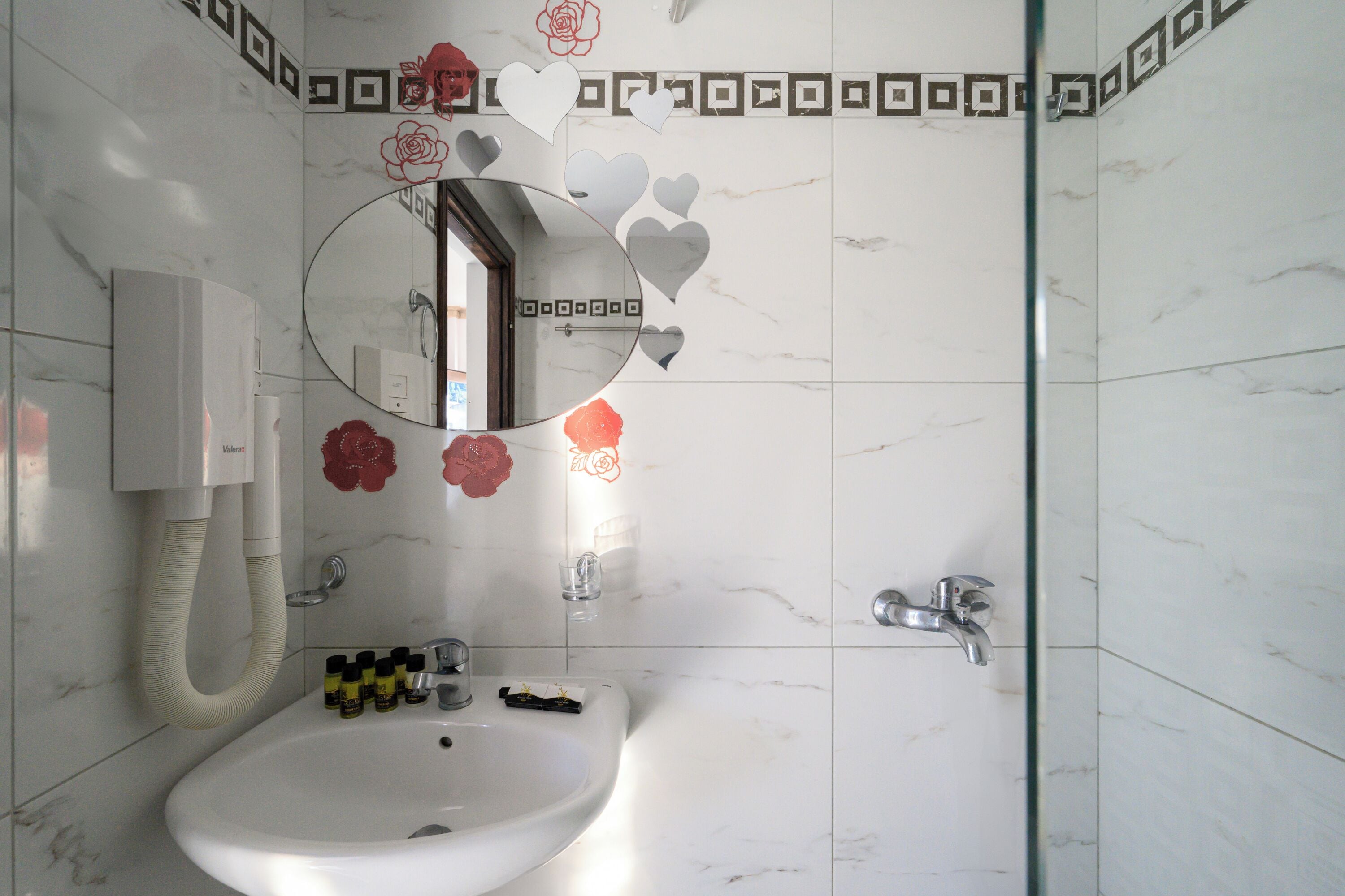 A bathroom with a white sink, a mirror, and a shower.