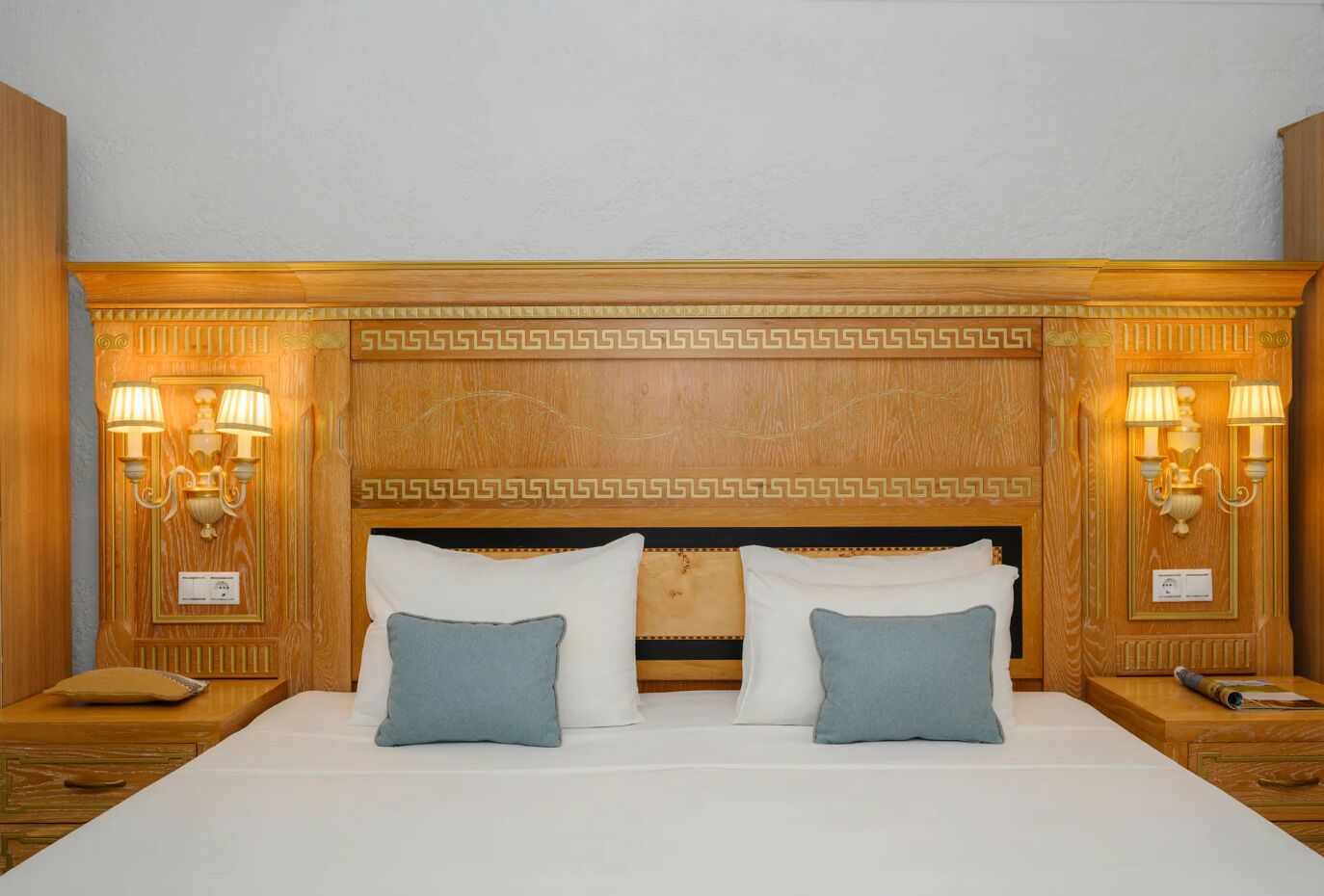 Una camera d'albergo con un letto grande, due comodini e applique a muro.