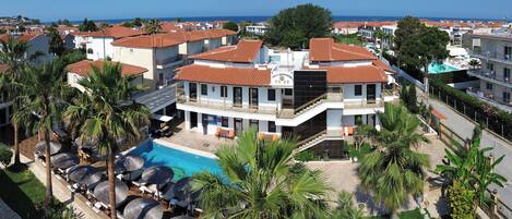 A resort with a pool, palm trees, and a view of the sea.