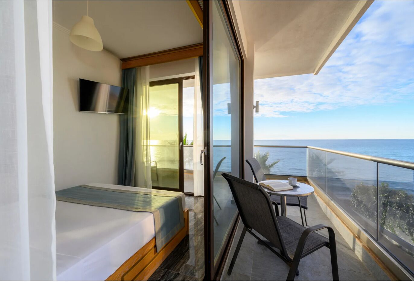 A balcony with a table and chairs, a bed, and a TV.