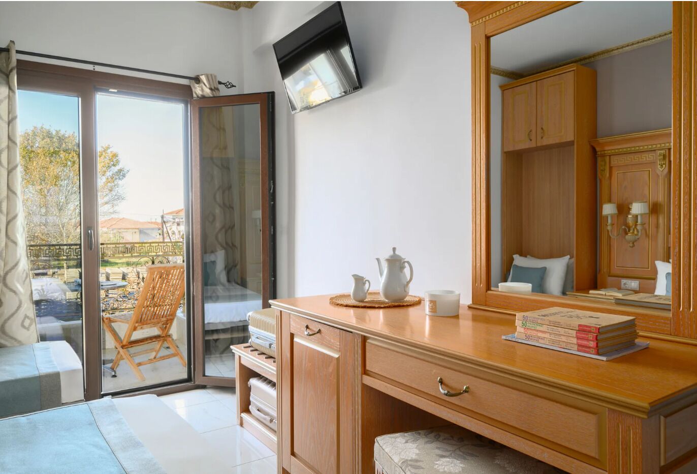 Une pièce comprenant un bureau en bois, une chaise, un lit, un téléviseur et une porte-fenêtre coulissante donnant sur un espace extérieur.