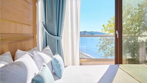 Une chambre avec un grand lit, une vue sur la mer et un balcon.