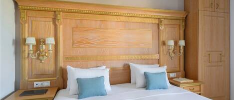 A hotel room with a large bed, two bedside tables, a nightstand, and a wardrobe.