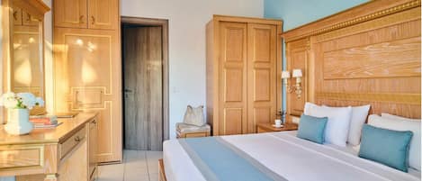 Una camera d'albergo con un ampio letto, un'armadio in legno, un comodino con lampade e una piccola zona salotto.