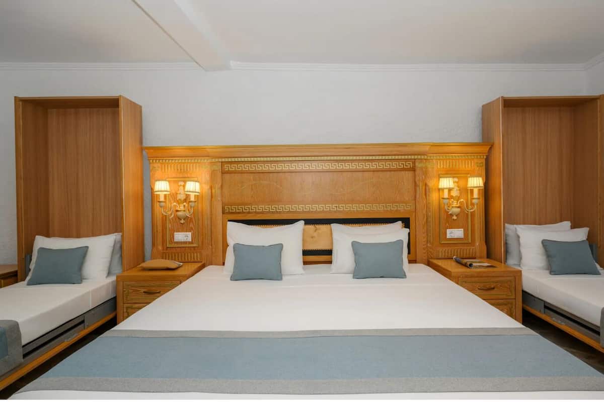 A double bed with a wooden headboard, two bedside tables with lamps, and a matching nightstand on each side.