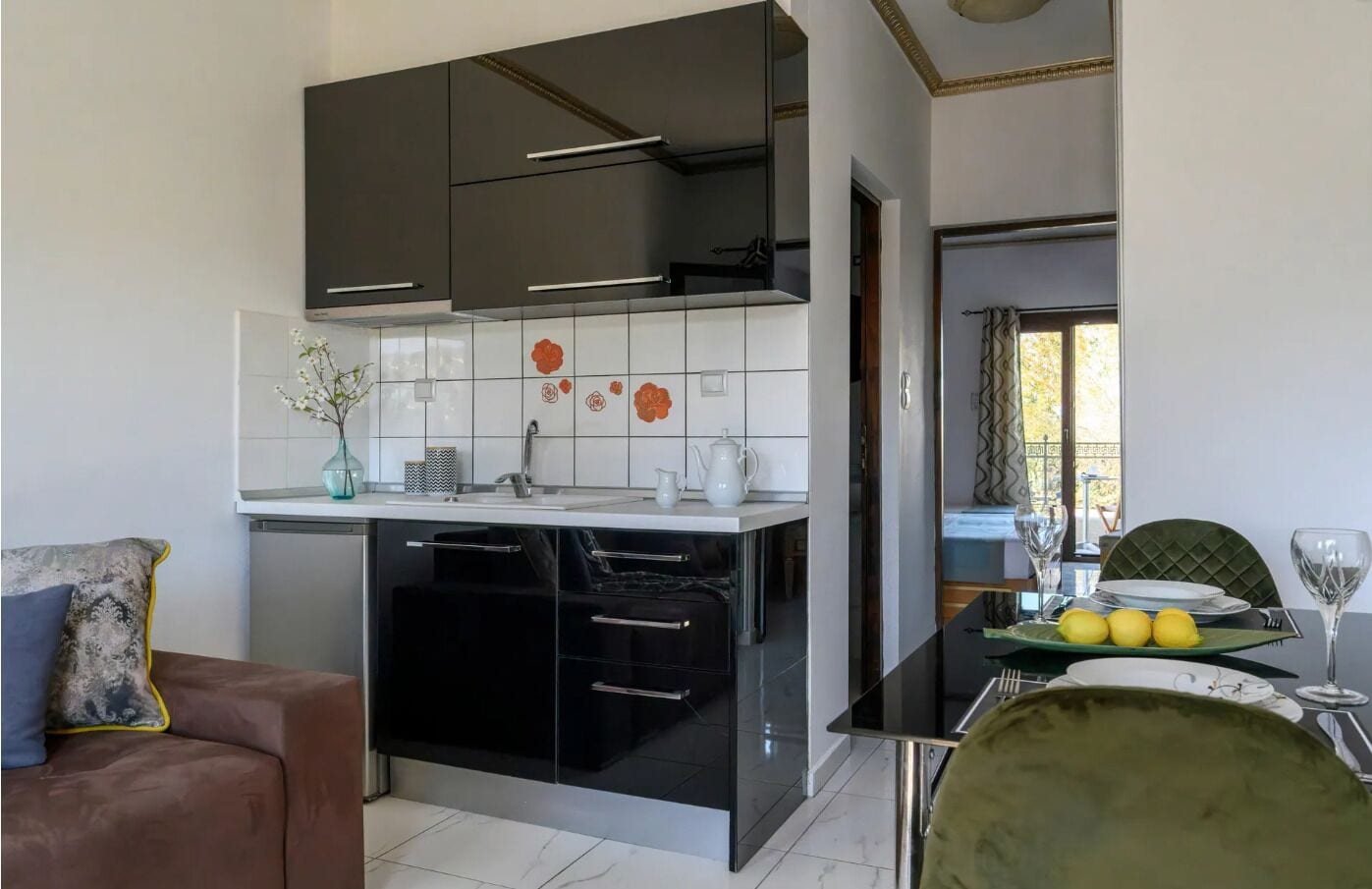 A modern kitchen with black cabinets, a white countertop, and a tiled backsplash.