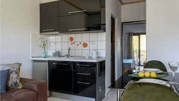 A modern kitchen with black cabinets, a white countertop, and a tiled backsplash.