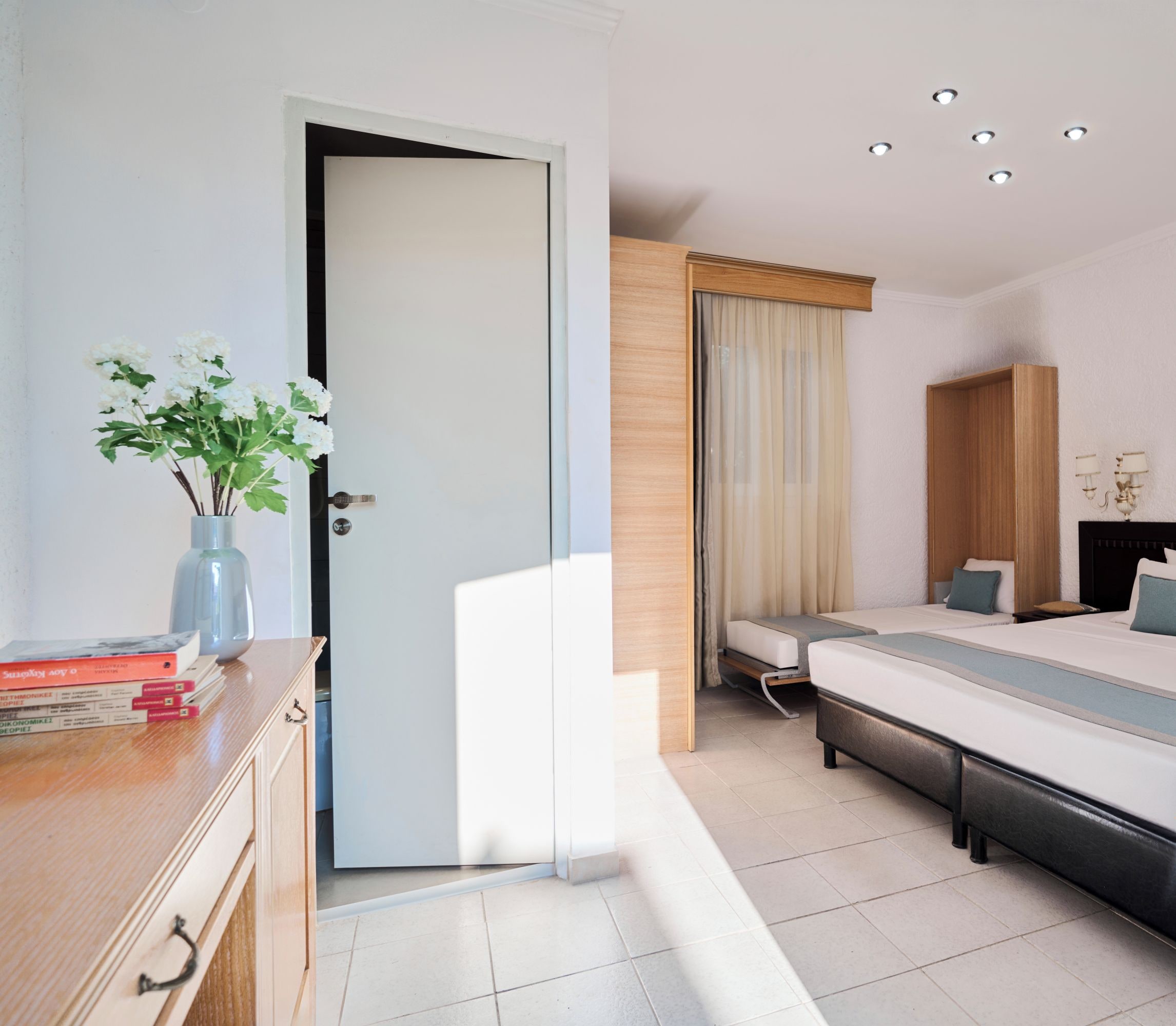 A modern hotel room with a large bed, bedside tables, a desk, and a window with curtains.