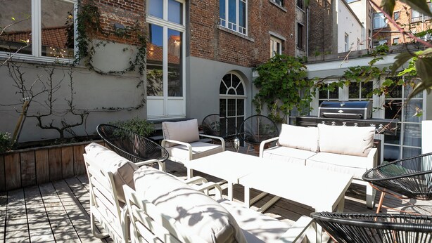 A patio area with outdoor furniture, including a sofa and chairs, a table, and a barbecue grill. - Fish Market Apartments (Brussels)