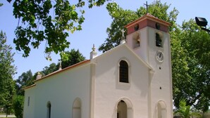 A small, single-story church with a bell tower and a clock.