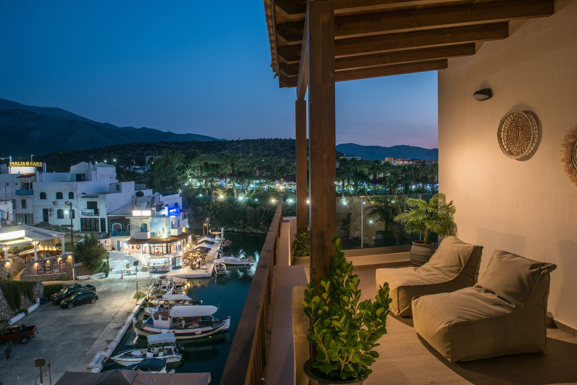 A balcony with a view of a marina and buildings, a potted plant, and a wall with a decorative item.