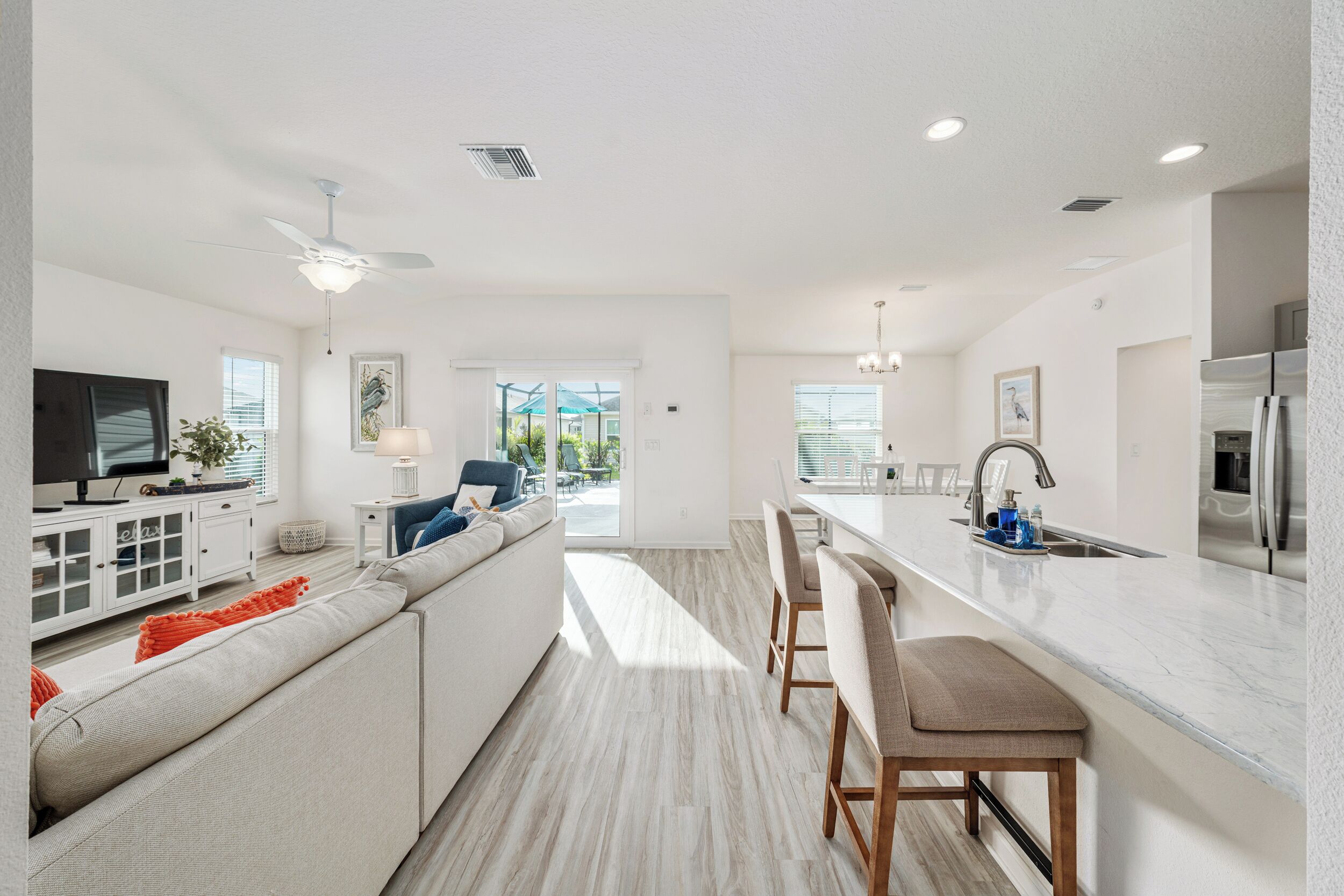A modern kitchen with a central island, bar stools, and a dining area.