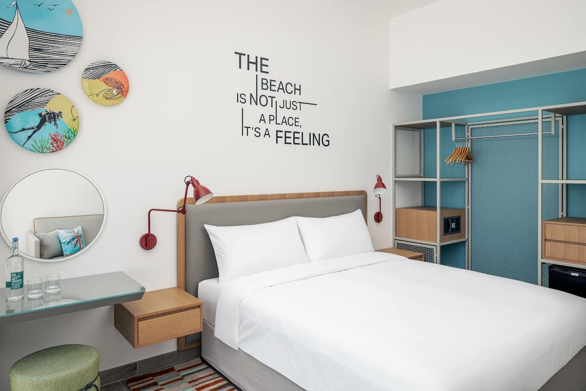 Una habitación de hotel moderna con una cama, mesita de noche y un armario.