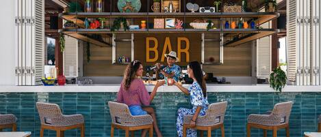 Un área de bar con un letrero que dice 'BAR', sillas de mimbre y un revoque de azulejos.
