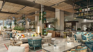 A modern interior with seating areas, tables, and hanging lights. - Rove Al Marjan Island (Ras Al Khaimah)