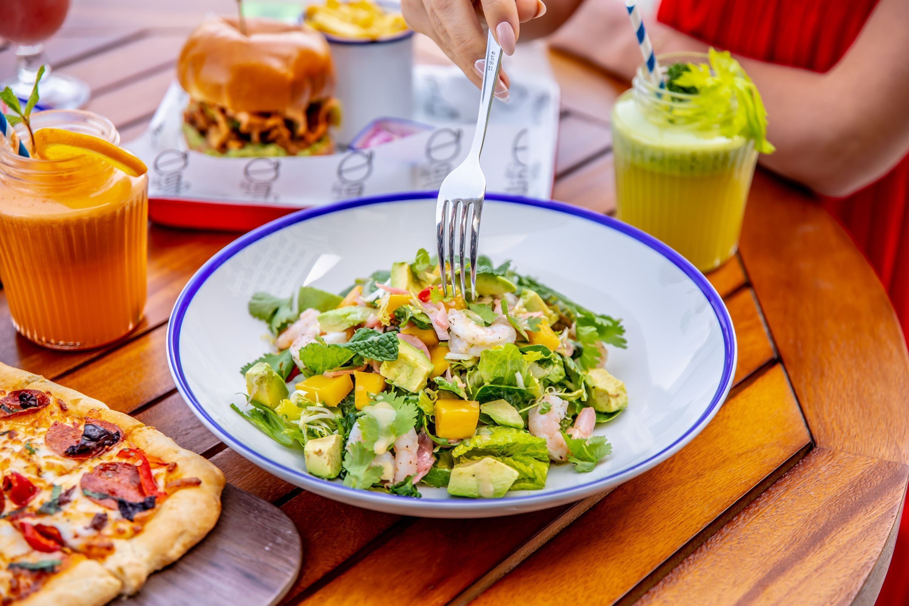 A plate of salad with a fork on a wooden table.